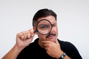 A suspicious middle-aged man inspecting something with a magnifying glass. Pondering the veracity and authenticity. Isolated on a white background.