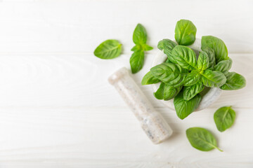 Fresh green basil in a mortar on a textured wooden background. Organic spices and herbs. Vegan. Fresh kitchen herbs. Fresh basil being made into pesto with mortar and pestle.Copy space. Place for text
