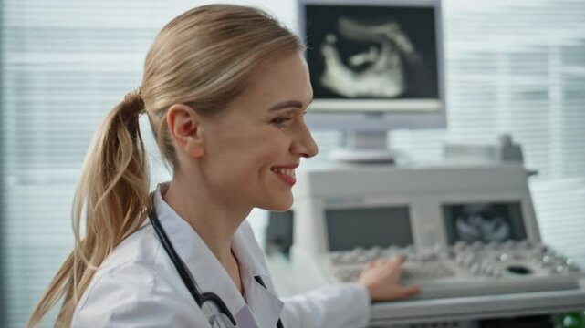 Doctor checking ultrasound monitor in clinic closeup. Smiling pregnant woman