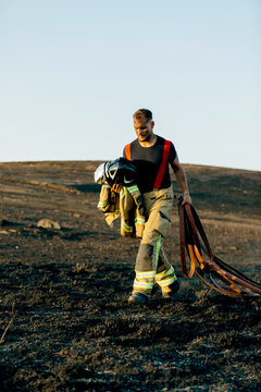 Firefighter walking through a burnt forest landscape