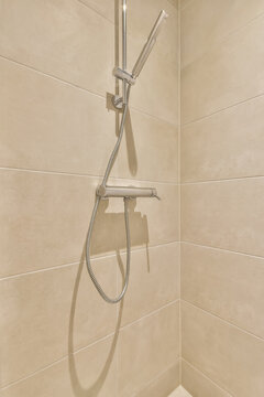 Modern shower head and hose in a tiled bathroom