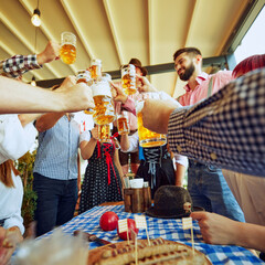 Cheers to German tradition, group of people in Bavarian and casual clothes, friends meeting at pub,...