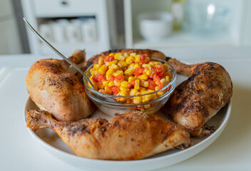 Homemade food with delicious fresh roasted chicken legs and a refreshing corn bell pepper salad on kitchen counter