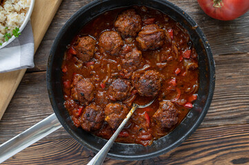 Delicious meatballs in a spicy brown sauce. Served ready to eat in a frying pan on rustic and wooden table background from above