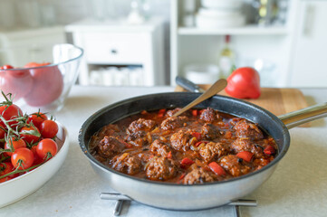 Homemade fresh cooked meatballs in a spicy pepper tomato sauce on kitchen counter in a frying pan