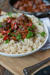 Braised meatballs in a spicy red pepper sauce or puszta sauce on a plate with brown rice