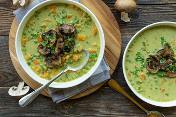 Vegetarian pea soup with pan fried mushrooms. Healthy homemade food on wooden table