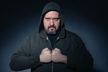 Man in his 40's with goatee, hoodie and black casual clothes looking at camera with angry...