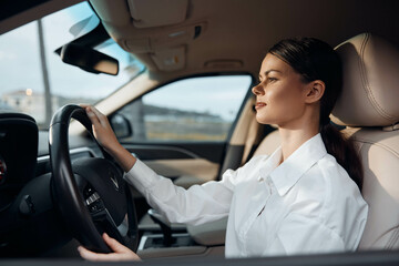 Woman, car, driver's seat, steering wheel a woman is seated in the driver's seat of a car, hand on the steering wheel, looking directly at the camera with a confident expression