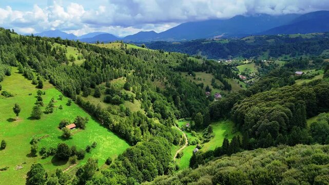 Aerial view of a picturesque countryside of Pestera panning up revealing clouds over mountain peaks