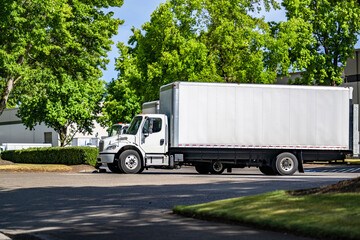 Middle duty day cab rig semi truck with long box trailer and lift on the back door standing on the...