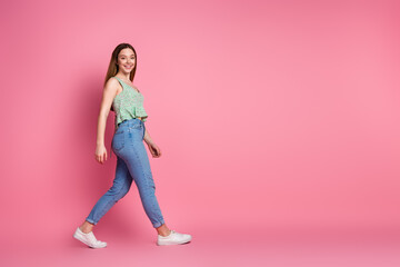 Full size profile photo of nice young girl walk empty space wear top isolated on pink color background