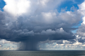 Cloudscape over the sea short before a thunderstorm with a rain shower going down to the water