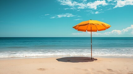 Fototapeta premium A bright yellow beach umbrella stands on a sandy beach, with the blue ocean and sky stretching beyond.