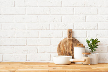 Kitchen accessories on wooden table with copy space over white brick wall background