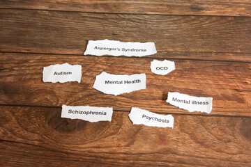 Mental health disorders on strips of paper on wooden table. 