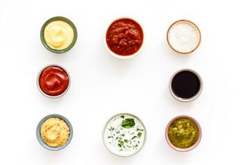 Set of bowls with sauces pesto salsa mustard and others, top view. Food background