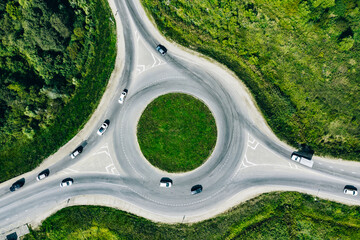 Aerial drone view of traffic roundabout and road junctions with cars in green summer season