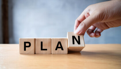 A hand is holding a wooden block with the word "plan" written on it