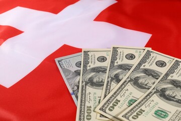 Swiss flag with U.S. dollar banknotes on display in close-up