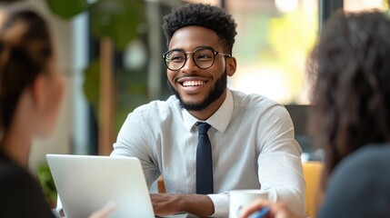 A content office worker in a tie, sitting at a conference table with a laptop open, engaged in a lively discussion with colleagues, showcasing teamwork.