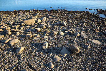 Obraz premium pebbles and stones on shore at evening light background