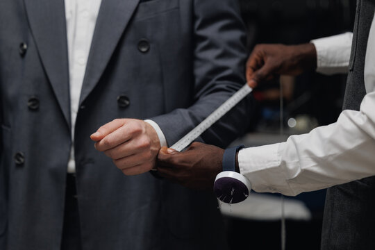Professional tailor measuring customer for bespoke suit in luxury designer atelier