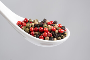 Different varieties of peppercorns, red, green, black and white peppers in a spoon