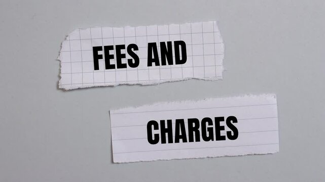 Fees and charges message writing on ripped torn paper pieces on gray background. Conceptual fees and charges symbol.