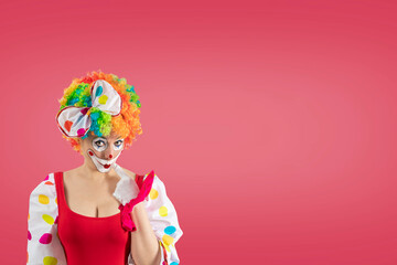 Offended female clown, woman entertainer dressed as a colorful Joker in a suit and wig, with clown...