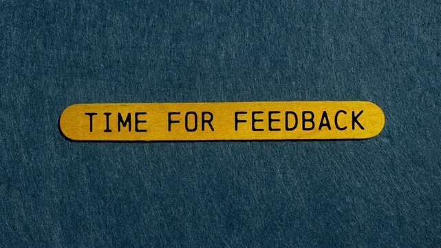 Time for feedback message writing on yellow wooden stick on gray felt background. Conceptual time for feedback symbol.