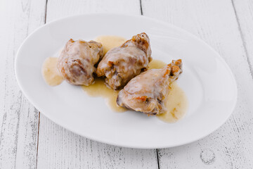 Roasted chicken legs with white wine sauce on white plate