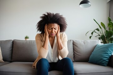 Obraz premium Woman Experiencing Disorientation and Intense Headache While Sitting on the Couch