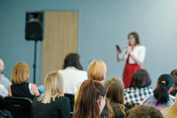 Business lecture with a female speaker addressing an engaged audience, discussing important topics related to the industry.