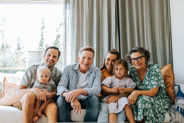 Happy multi-generational family sitting together on sofa at home