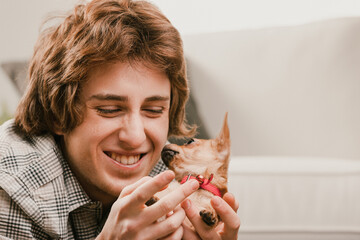Young man holding and playing with his puppy dog at home