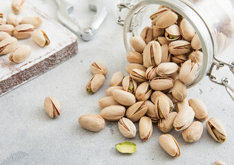 Salted pistachio nuts snack in glass jar on white kitchen table.Macro.