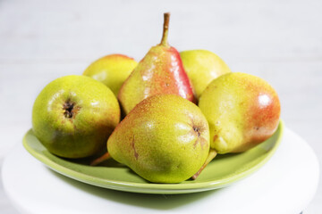 Ripe pears with water drops on green plate