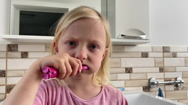 Young girl diligently brushes her teeth in a brightly lit bathroom, emphasizing good oral hygiene