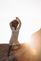 Young african woman posing against background of sandy canyon at sunset.