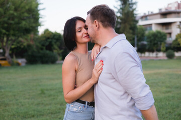 A happy smiling couple walking, hugging and kissing in park on late summer sunset