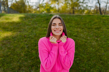 young smiling woman in pink sweater walking in green park