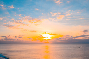 Vibrant sunset over a calm ocean, with golden sunlight reflecting off the water and colorful sky