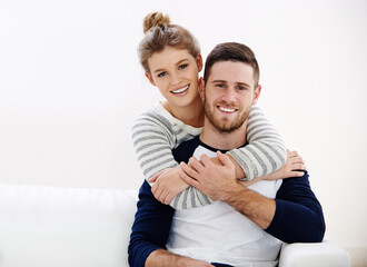 Obraz premium Portrait, hug and happy couple in home with love, care and bonding together on sofa. Face, man and woman piggyback in living room for connection, healthy relationship and support partner in marriage