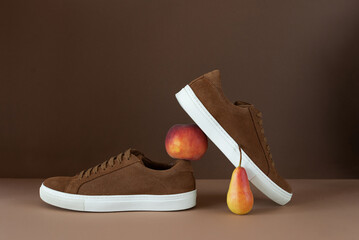 Still life of brown men's minimalist boots with white sole on beige and brown background. Autumn...