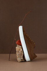 Still life of brown men's minimalist boots with white sole on beige and brown background. Autumn...