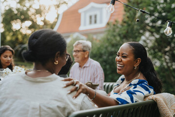 Cheerful mid adult woman having fun with female family member at garden party