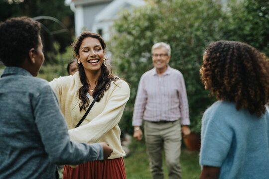 Cheerful teenage girl greeting family members at social gathering in back yard