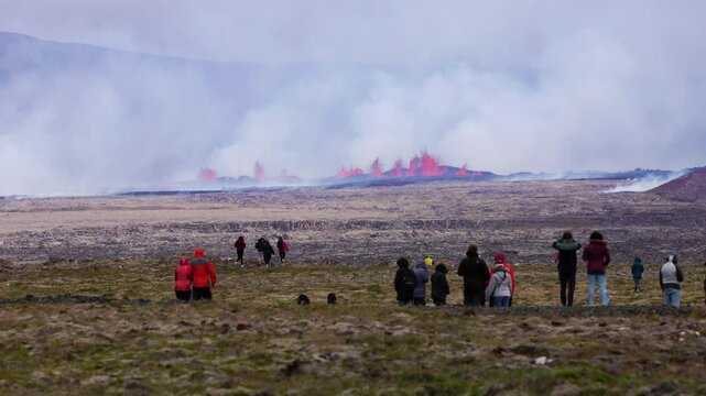Tourists look at and walking towards volcanic eruption on the Reykjanes peninsula in Iceland.
