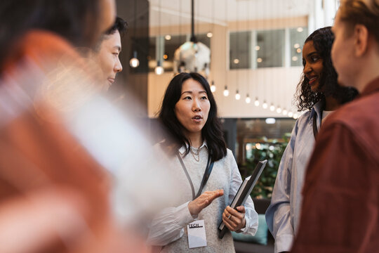 Female entrepreneur discussing business strategy with delegates in seminar at convention center